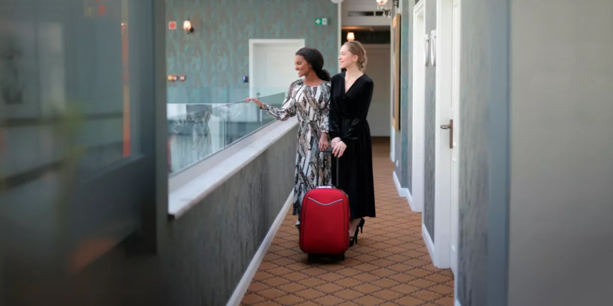 Zwei elegante Damen mit einem roten Koffer in einem modernen Hotel