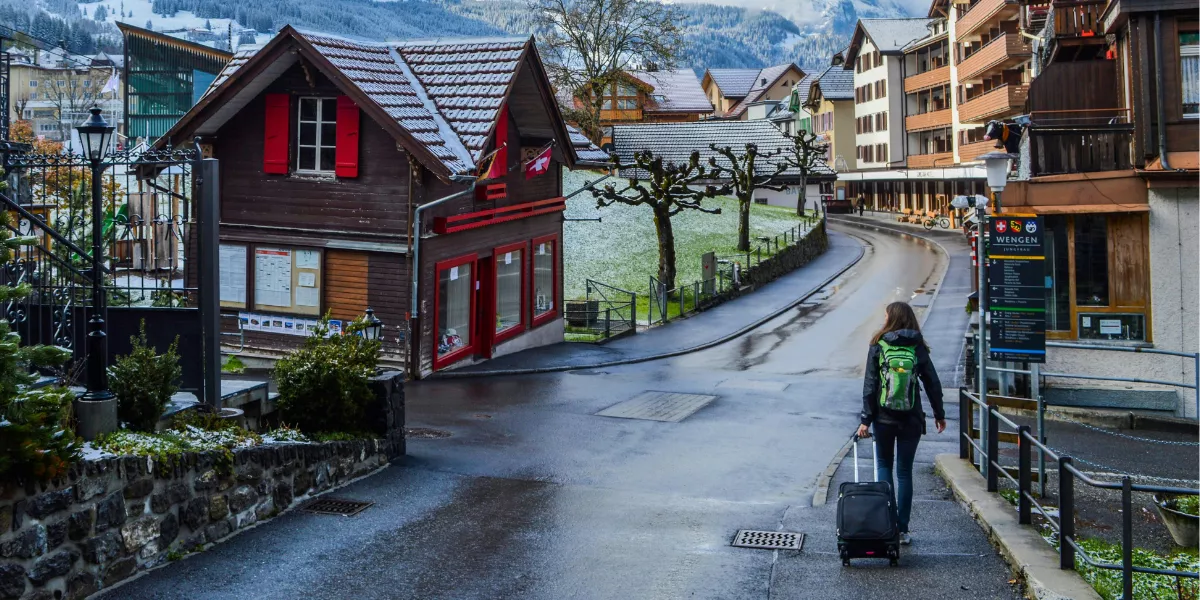 Eine Frau spaziert durch ein ländliches Dorf in der Nähe schneebedeckter Berge